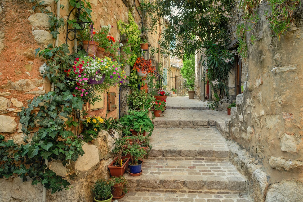 ours-journey Beautiful cobblestone alley in France adorned with colorful flowers and stone architecture.