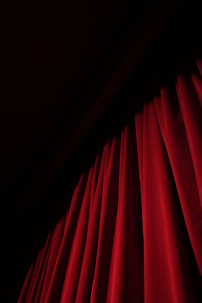 A striking red velvet curtain with dramatic lighting in a theater setting, offering ample copy space.